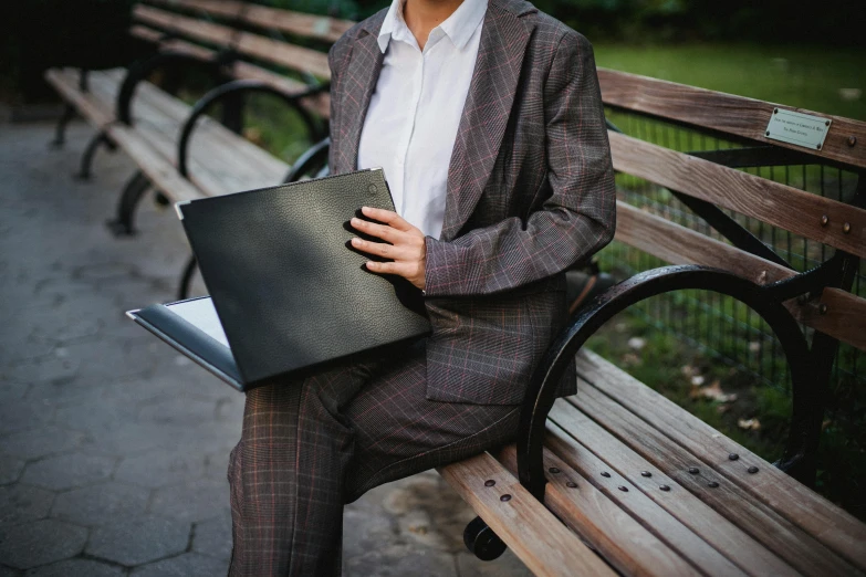 a young man sitting on top of a wooden park bench