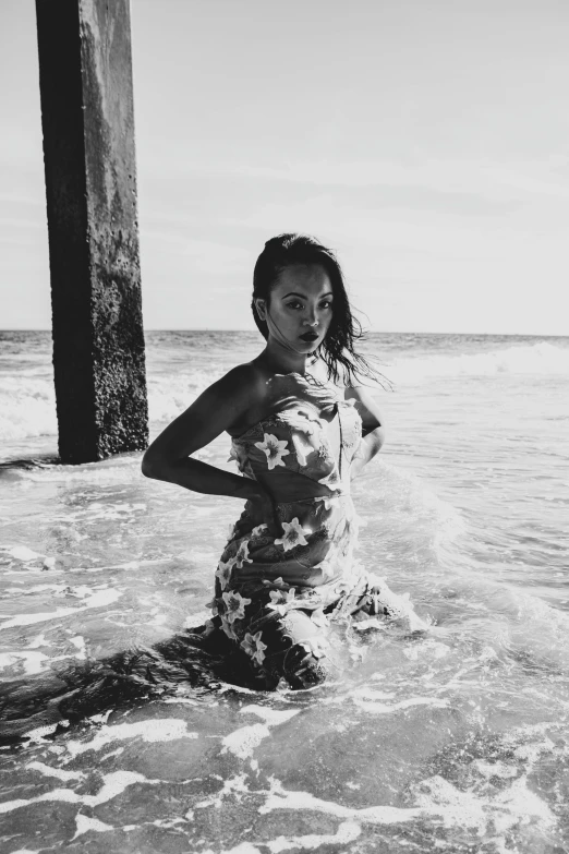 a woman standing in the ocean and holding her hand on her hip