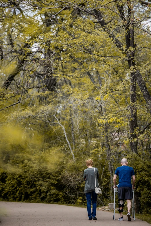 two people walk along the path in a wooded area