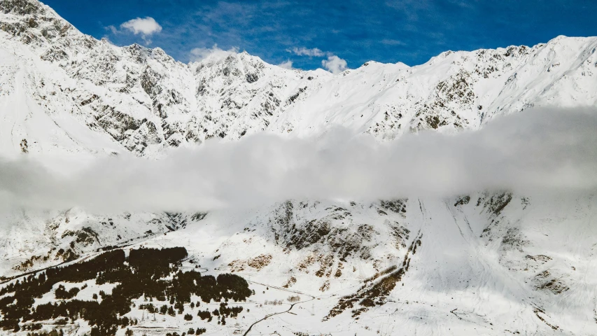 mountains, snow, and clouds in a blue sky