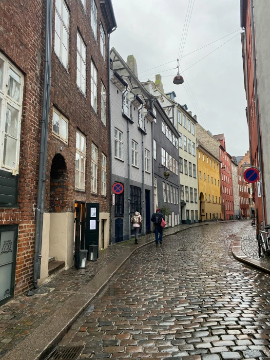 several buildings along the street as pedestrians walk on the cobblestone