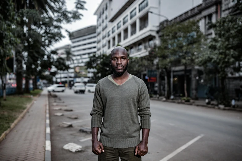 a man in a green sweater standing on a street