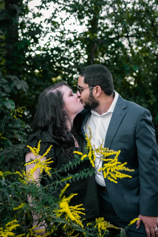 a man and woman who are kissing while standing among plants