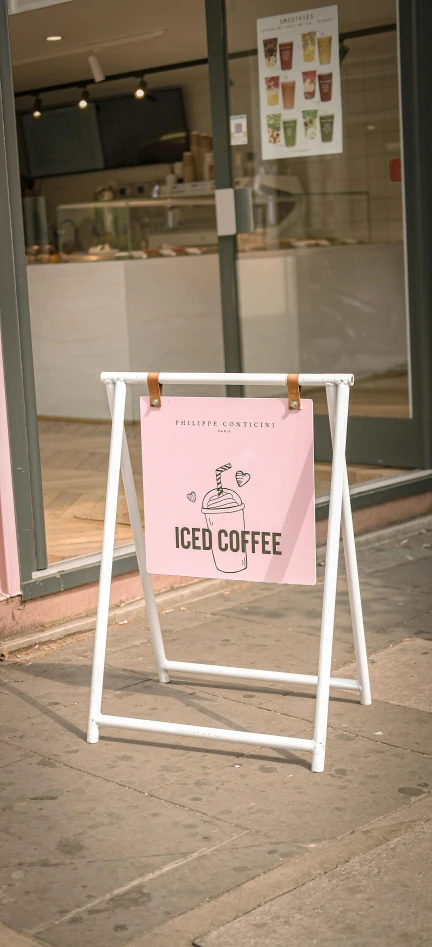 a sign sitting on the sidewalk outside of a iced coffee shop