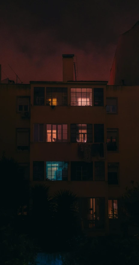 the building at the end of a dark sky, is lit up by the window