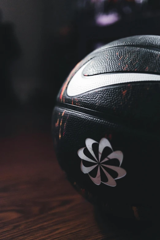 a black basketball with a floral pattern sitting on top of a wooden table