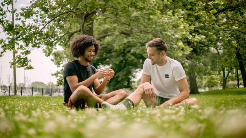 two young men sitting on the grass talking