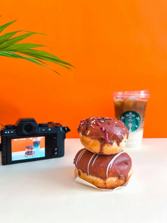 two donuts sitting on top of a bag next to a camera