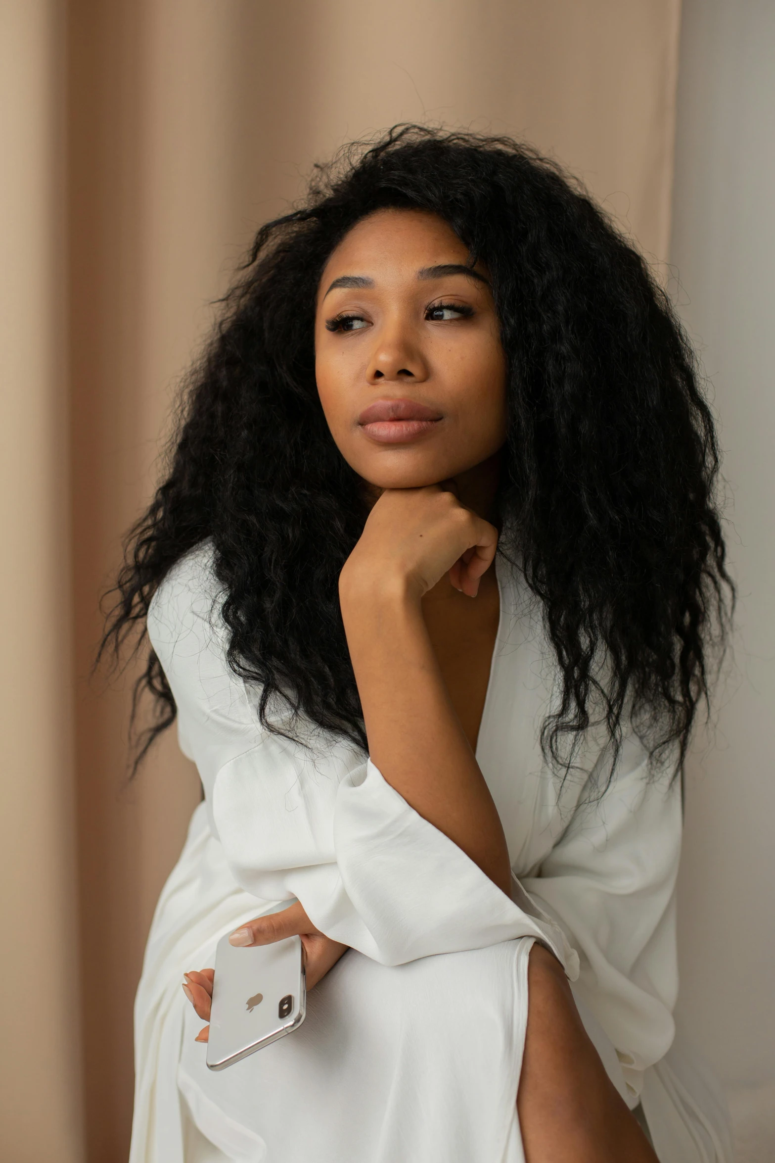 the woman poses with her cell phone near her chest