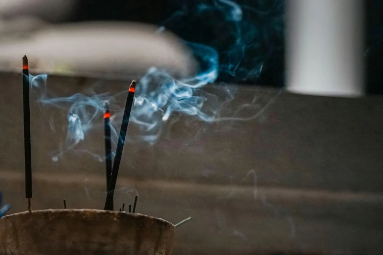 smoke from incense sticks in a pot that is being used for smoking