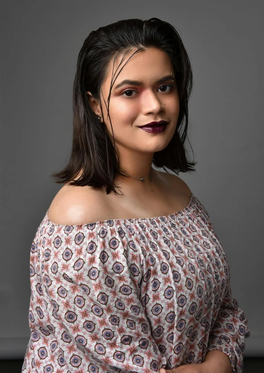 a woman wearing a off - shoulder top smiles at the camera