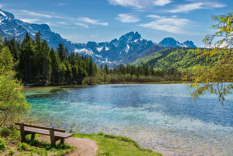 a bench is shown in front of a lake and mountains