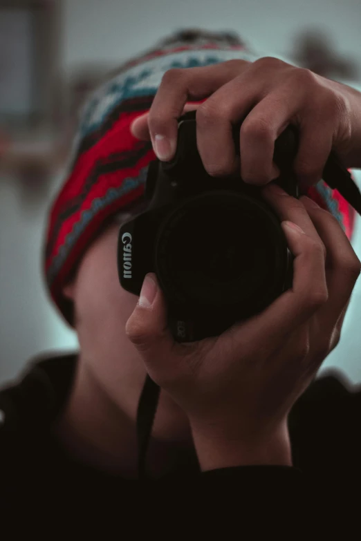 man in striped cap taking pograph with camera