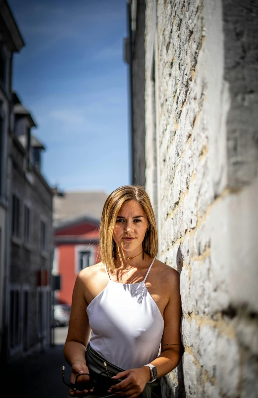 woman in a white tank top standing outside the wall