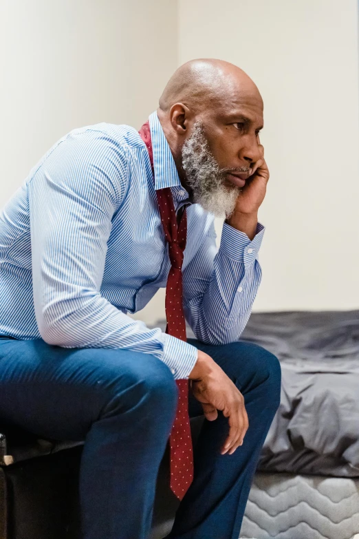 a bald man sitting on top of a suitcase