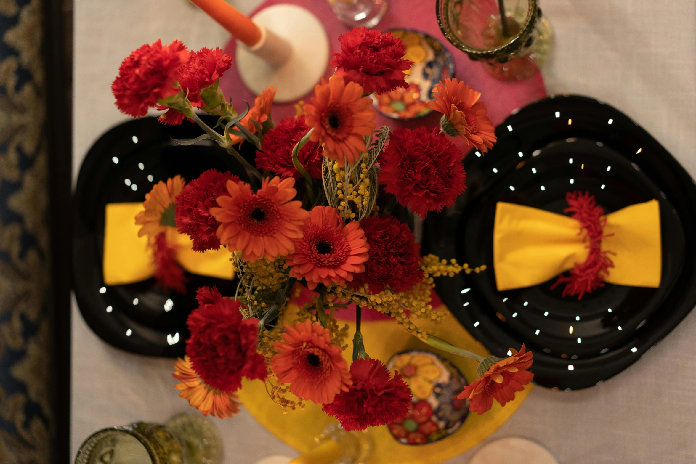 a table with yellow, black and red plates with flower decorations