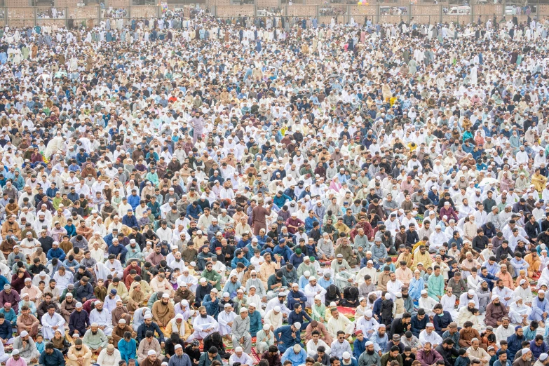 a large group of people standing and sitting in the middle of a field