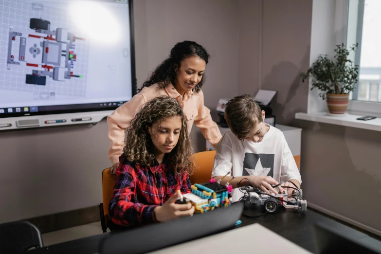 three children play with toy cars on a table