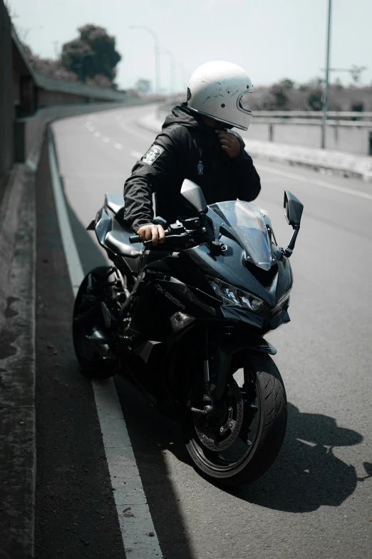 man riding black motorcycle with white helmet on the side