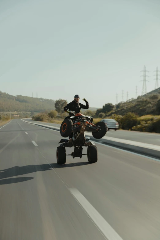 person riding quad bike down the highway on four wheels