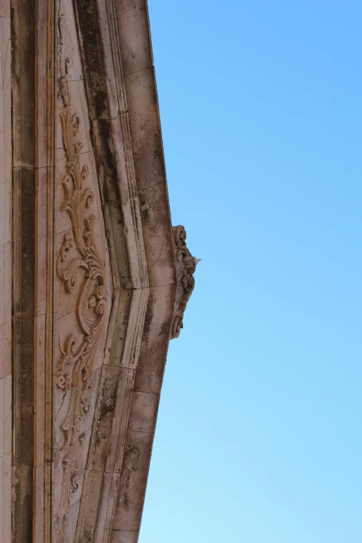 the corner of an old stone structure looking up at blue sky