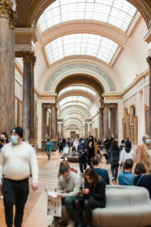 a long hall has vaulted ceilings and people in it