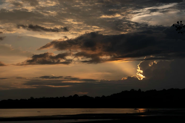 an orange and purple sunset over water with clouds