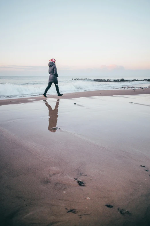 a man walking across a beach holding a frisbee