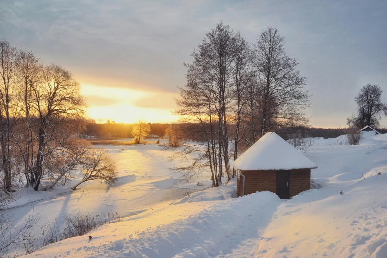 a sunset over a snowy hillside with small log cabins in the foreground