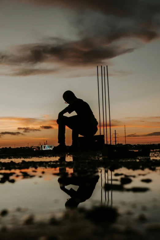 the silhouette of a person sitting on a boat at sunset