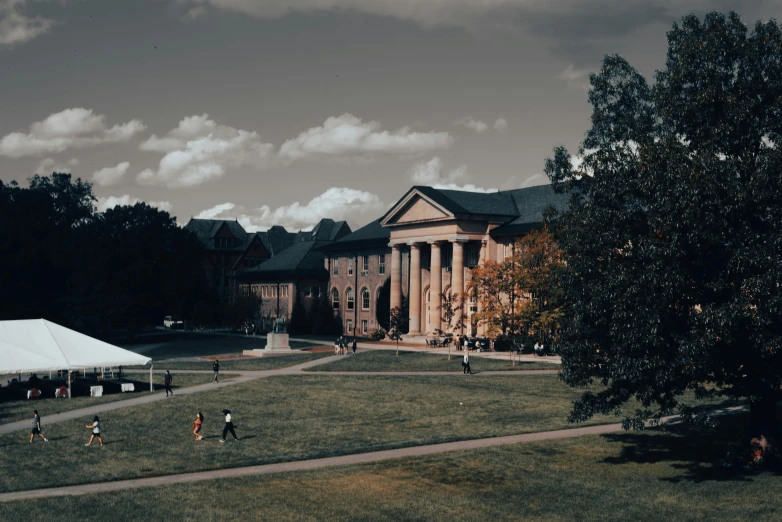 people walking across a field in front of a large building