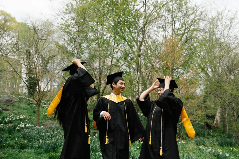 three young men standing together, in gowns and cap and gown