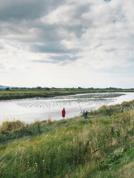 a man fishing in the river on a cloudy day