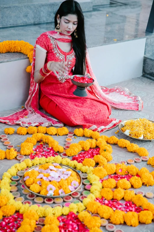 girl dressed in red sitting on steps with flower petals surrounding her