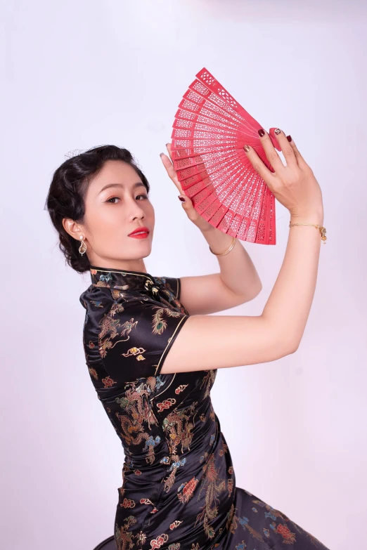 the woman in the evening dress holds up a pink fan