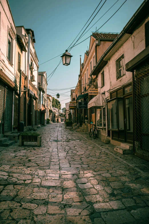 an old street lined with small buildings under street lamps