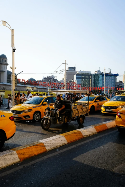 yellow taxis driving down a busy street next to tall buildings