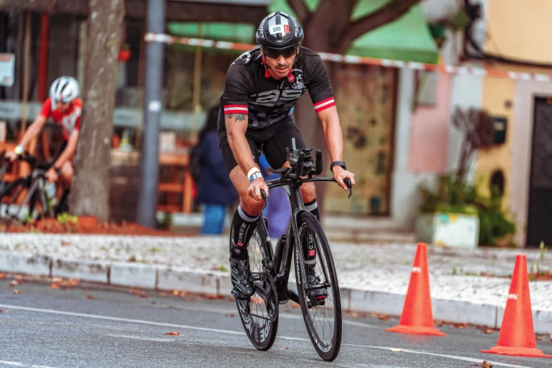 the cyclist is racing his bike around an orange cone