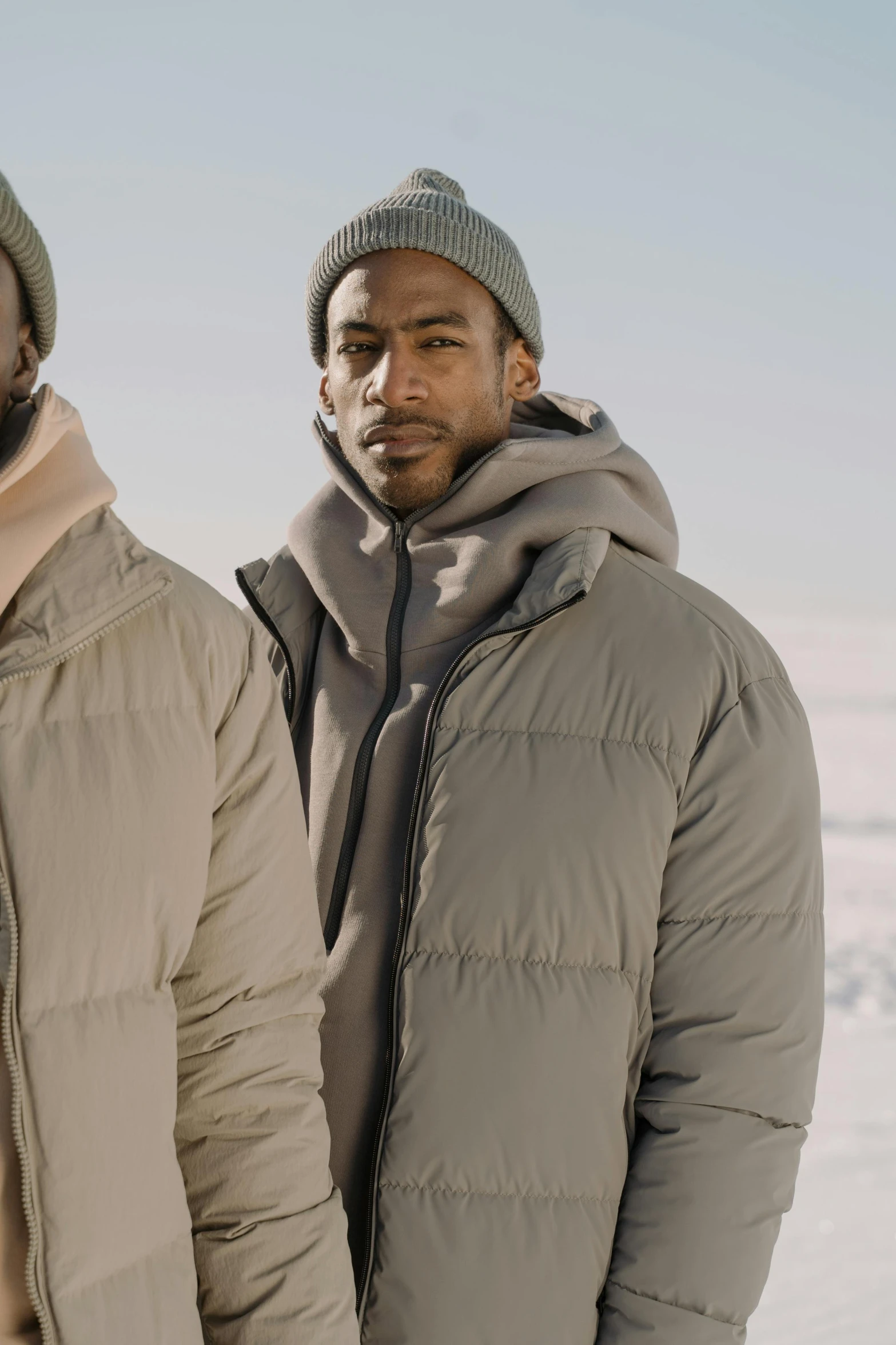 two men are standing side by side in winter coats