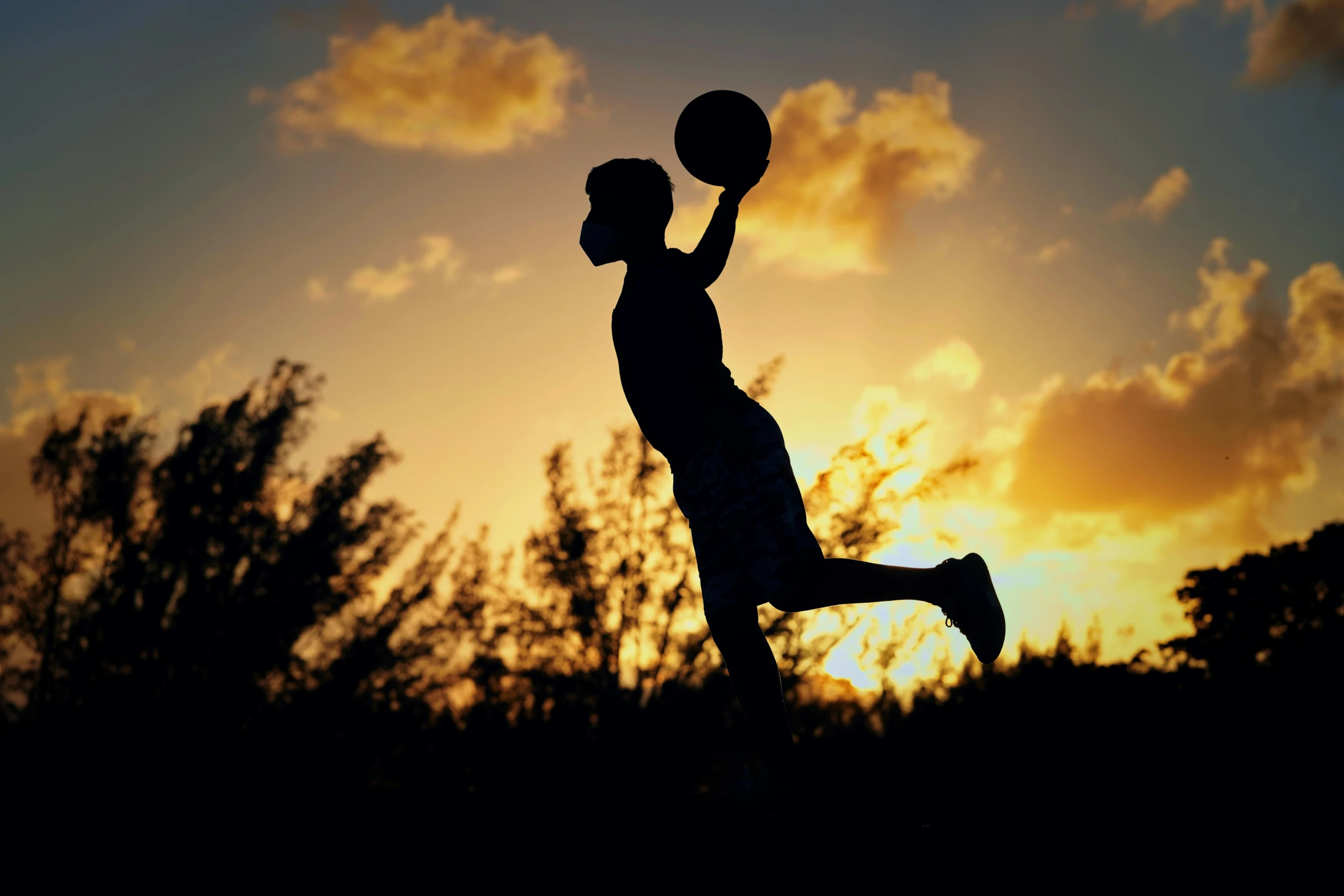 a silhouette of a person dunking at sunset