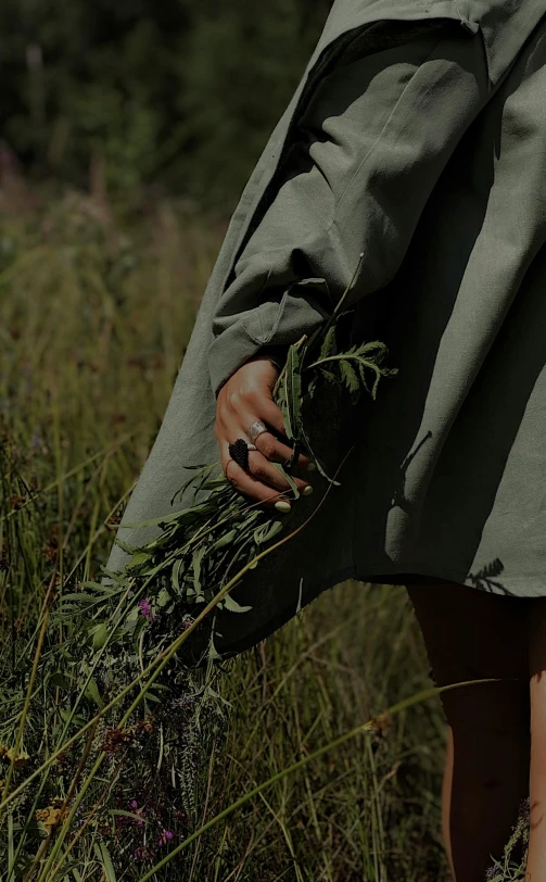 a woman in an overcoat carrying weeds