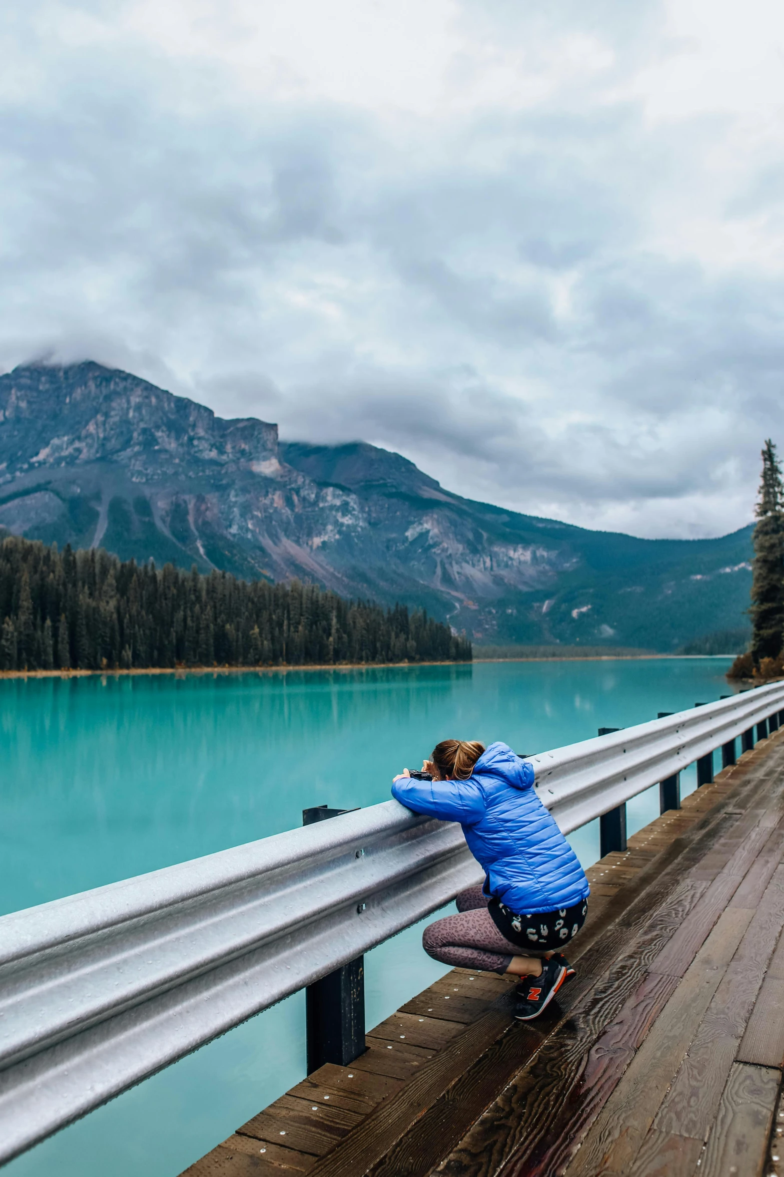 a woman leaning against a bridge looking over the water