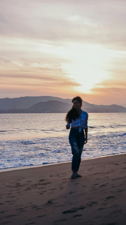 the woman is walking down the beach by the water