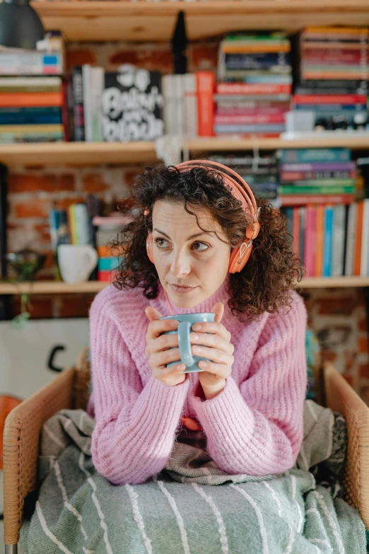 a woman sitting on a chair in front of bookshelves and looking at the camera