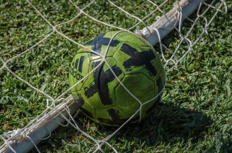 the green ball is in front of a soccer net