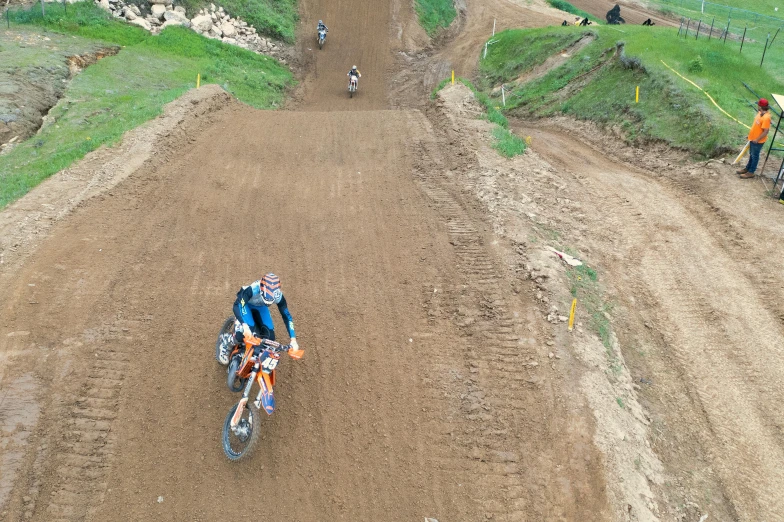 two motorcyclists in orange jerseys in the dirt