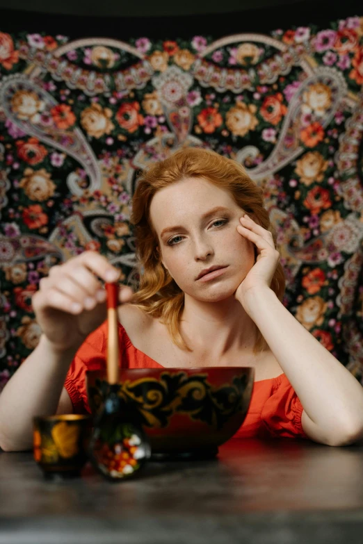 woman posing next to colorful cloth and bowl of fruit