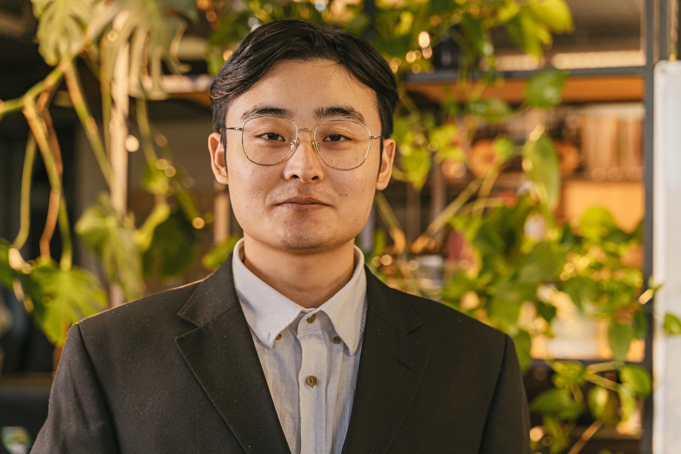 a man with glasses is standing in front of plants