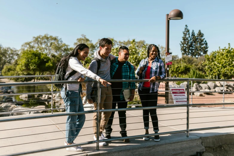 two men and two women are standing near a man riding a skateboard