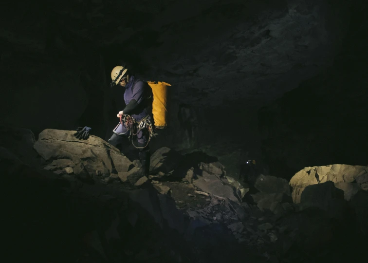 a man wearing an orange and yellow backpack and walking into the dark